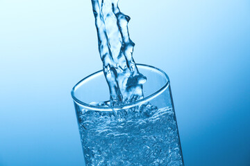 Pouring soda water into glass on light blue background, closeup