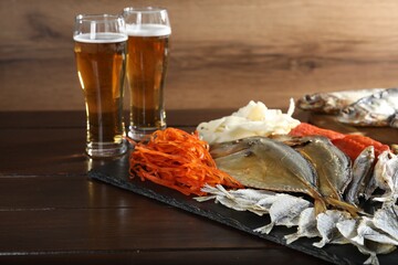 Tasty beer and dried fish snacks on wooden table, closeup