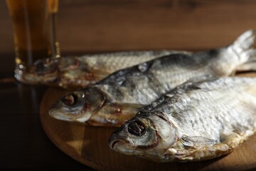 Dried salted roach fish and beer on table, closeup