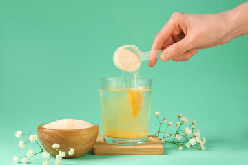 Woman adding collagen powder into glass with water on turquoise background, closeup