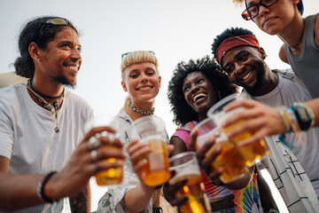 Happy friends toasting with beer glasses at music festival