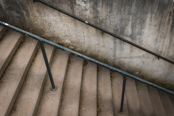 Concrete stairs leading down with a railing against a weathered wall in an urban setting