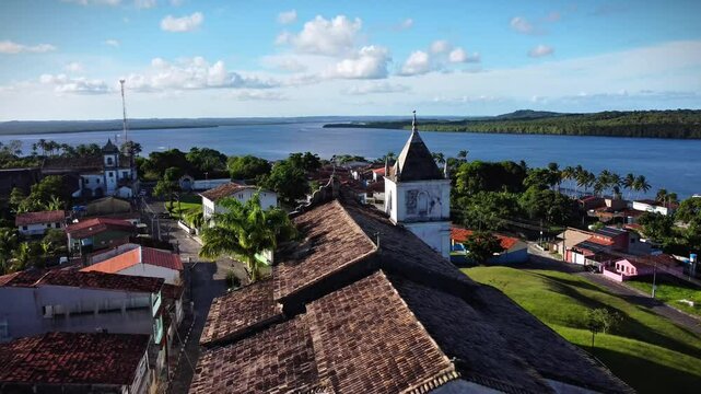 aerial view of a small village in Bahia state with a church in the ground zero during sunny day, river and a dense forest