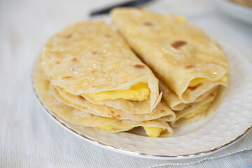 Traditional tatar Qystybiy - thin pancakes, beautifully folded and stacked on a white plate, filled with mashed potatoes, create a tempting breakfast delight