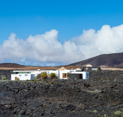 White Buildings Amidst Volcanic Landscape Under Blue Sky