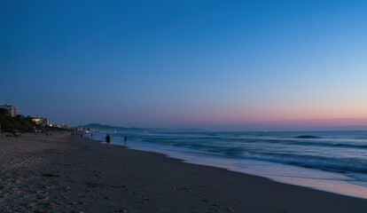 Obraz premium People enjoying a relaxing evening stroll on the beach at twilight,