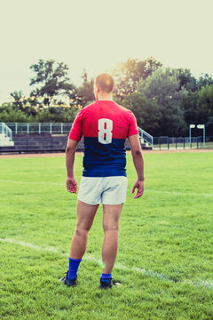 Rugby player from behind on rugby stadium, in sunset