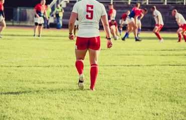 Rugby player walking on the field, and blurred players in the background