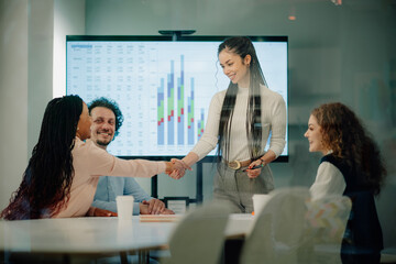 Obraz premium Businesswomen shaking hands after successful presentation in modern office meeting room