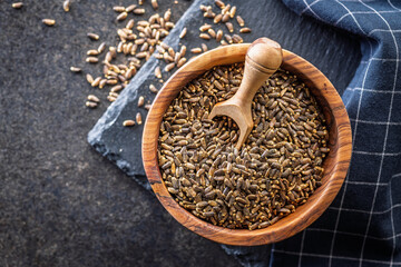 Milk thistle seeds in bowl on black table. Top view.