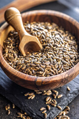 Milk thistle seeds in bowl on black table.
