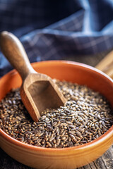 Milk thistle seeds in bowl on wooden table.