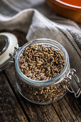 Milk thistle seeds in jar on wooden table.