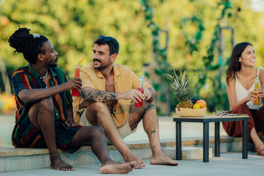 Friends enjoying summer vacation drinking cocktails by the poolside - Powered by Adobe