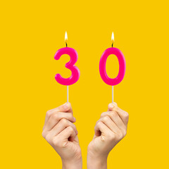 Birthday number 30 - Hands holding fuchsia colored candles
