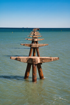 Remains of the structure of an old jetty in the Port of Sagunto, Valencia, Spain. Vertical photograph in the year 2025.
