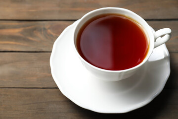 Refreshing black tea in cup on wooden table, closeup