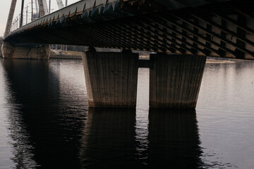 A striking perspective of a cable-stayed bridge over a calm river, showcasing urban infrastructure and architectural design