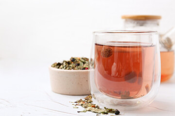 Delicious herbal tea and dry leaves on white table, closeup. Space for text