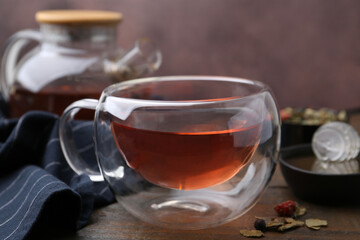 Delicious herbal tea with honey and dry leaves on wooden table, closeup