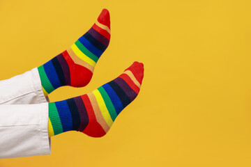 Woman wearing socks in LGBT colors on orange background, closeup. Space for text