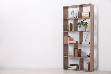 Wooden shelving unit with different home decor and houseplant near white wall indoors, space for text