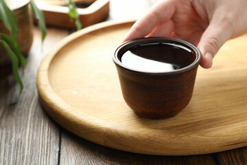 Woman with freshly brewed tea at wooden table, closeup