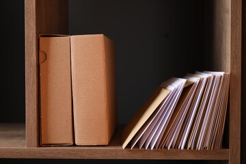 Different paper envelopes and parcels on wooden shelf in post office, closeup