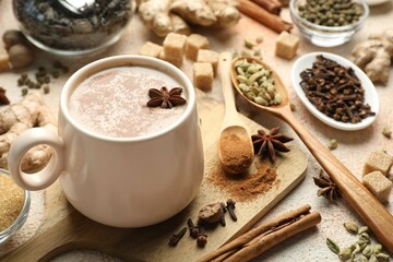 Aromatic Masala tea in cup, spices and brown on color textured table, closeup
