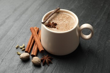 Aromatic Masala tea in cup and spices on black table, closeup