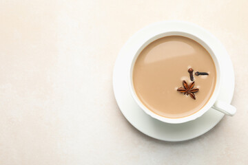 Aromatic Masala tea in cup and spices on light grey table, top view. Space for text