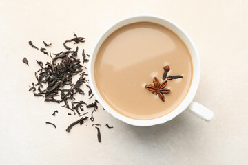 Aromatic Masala tea in cup, dry leaves and spices on light grey table, flat lay