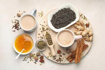 Aromatic Masala tea in cups, spices, dry leaves and honey on light grey table, flat lay