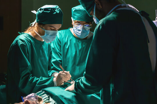 emergency doctor operating surgery procedure patient in operation theater using tools. staff team with masks practice occupation. specialist surgical group performing medical operation helping person