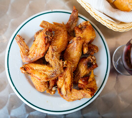 Picture of dish of tasty fried chicken wings served at plate on table