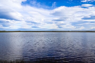 Panoramic view of lake reflecting clouds in Iceland under blue sky