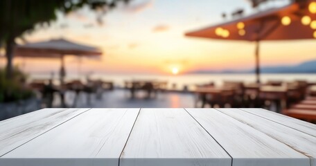 Une table en bois blanc avec un arrière-plan flou représentant un restaurant en plein air et une vue sur la mer au coucher du soleil, concept de présentation de produits ou une publicité.