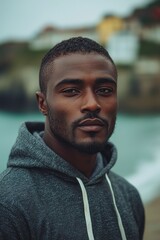 Fototapeta premium Portrait of a serious man wearing a hoodie near a scenic waterfront