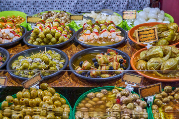 Variety of olives, pickles and skewers at a gourmet food market