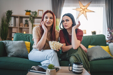two women caucasian teenage friends or sisters watch movie tv at home