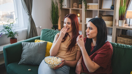 two women caucasian teenage friends or sisters watch movie tv at home