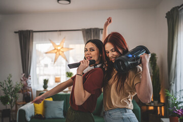 two women friends or sisters have fun at home females dance and sing