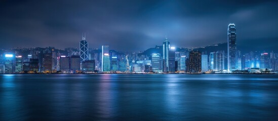 Naklejka premium Illuminated Hong Kong Skyline at Night with Calm Water
