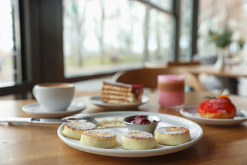 Delicious cottage cheese pancakes, desserts and aromatic coffee served on wooden table in cafe