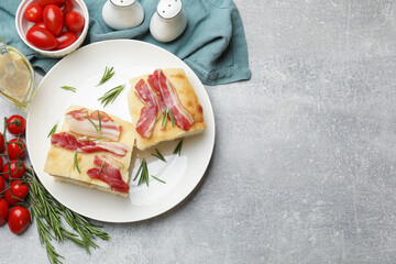 Pieces of delicious focaccia bread with bacon served on grey table, flat lay. Space for text