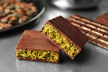 Pieces of tasty Dubai chocolate with pistachios and knafeh on grey table, closeup