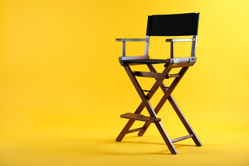 One empty director's chair on yellow background, space for text