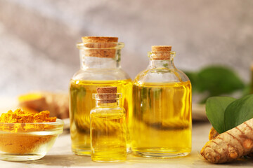 Turmeric oil, powder, root and green leaves on grey table, closeup