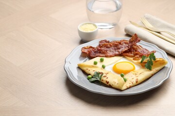 Delicious crepe with egg, bacon and green peas served on wooden table, space for text. Breton galette