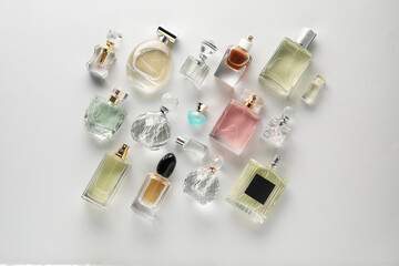 Bottles of various perfumes on light background, flat lay